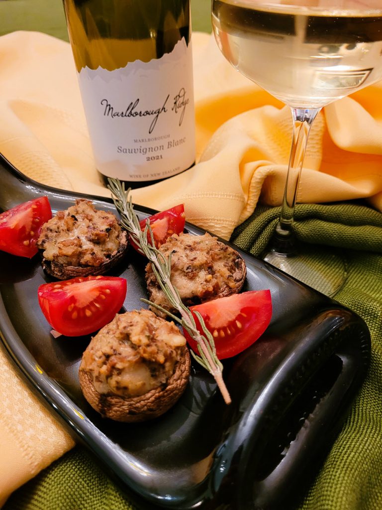 Cheese-stuffed mushrooms set out with quartered tomatoes