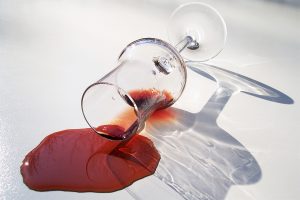 A spilled glass of red port on a white tablecloth